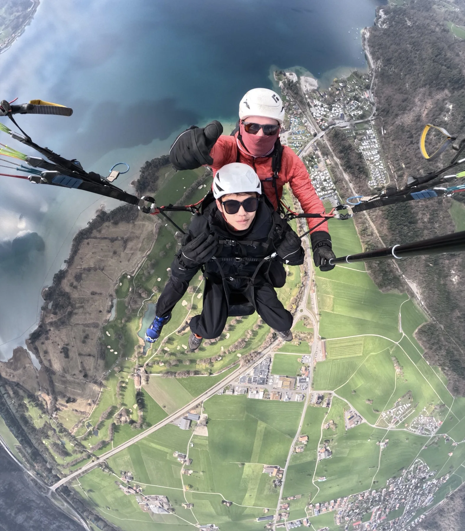 In-flight view of a turquoise lake from a tandem paraglider near Interlaken
