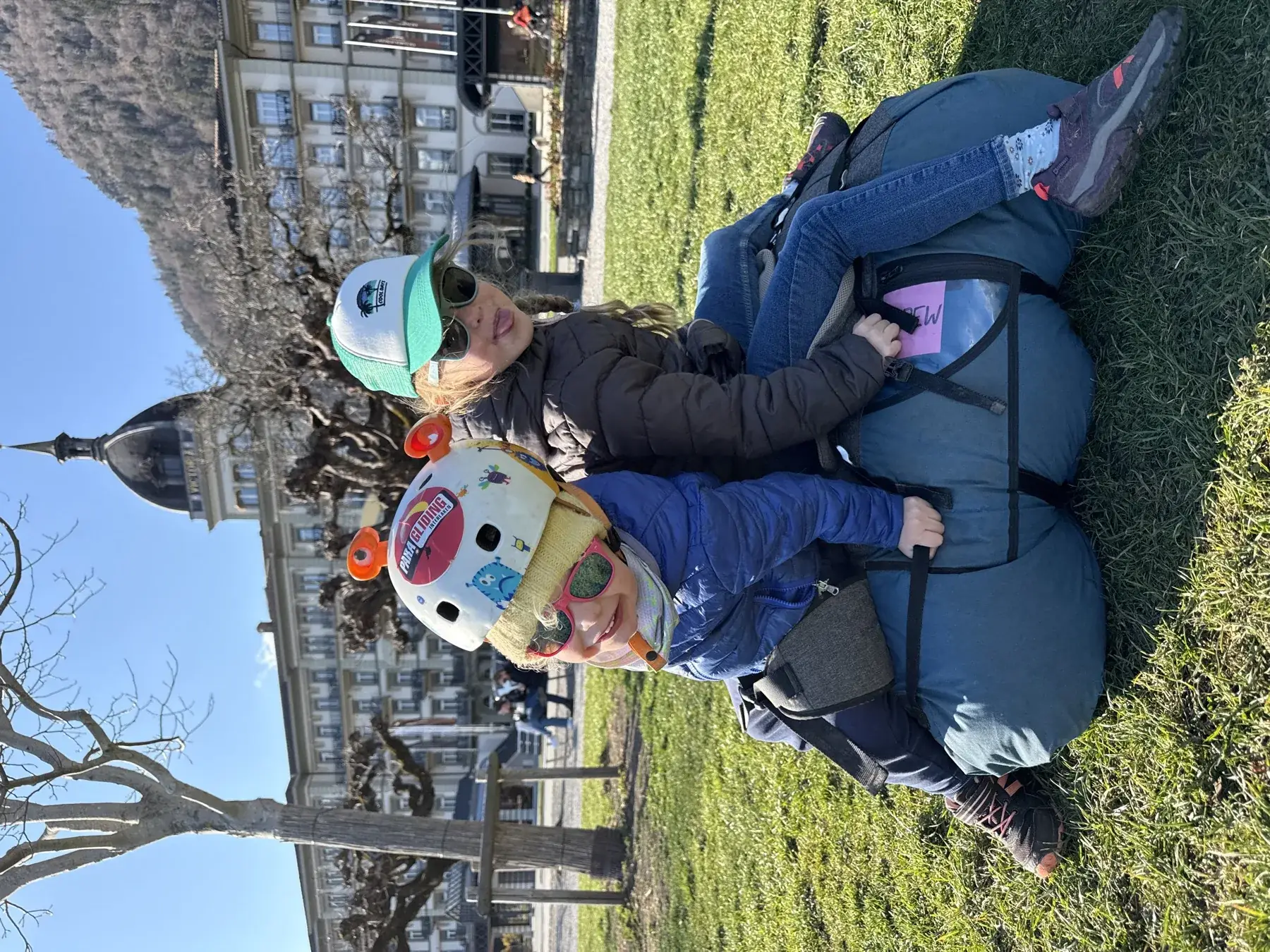 Children with paragliding gear on the Höhematte landing field in Interlaken with the Victoria-Jungfrau hotel behind