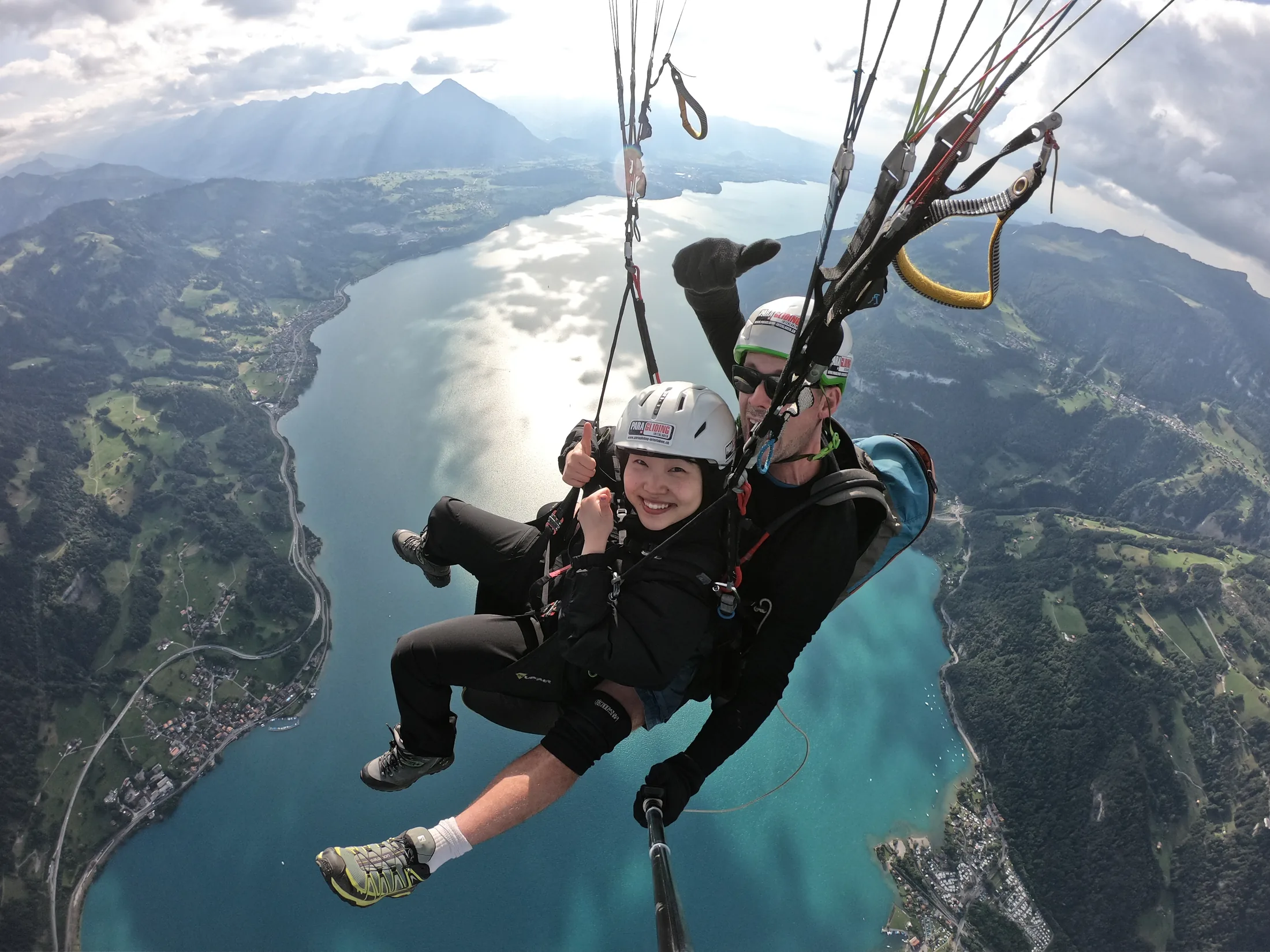 Tandem passenger giving a thumbs up over a turquoise lake near Interlaken